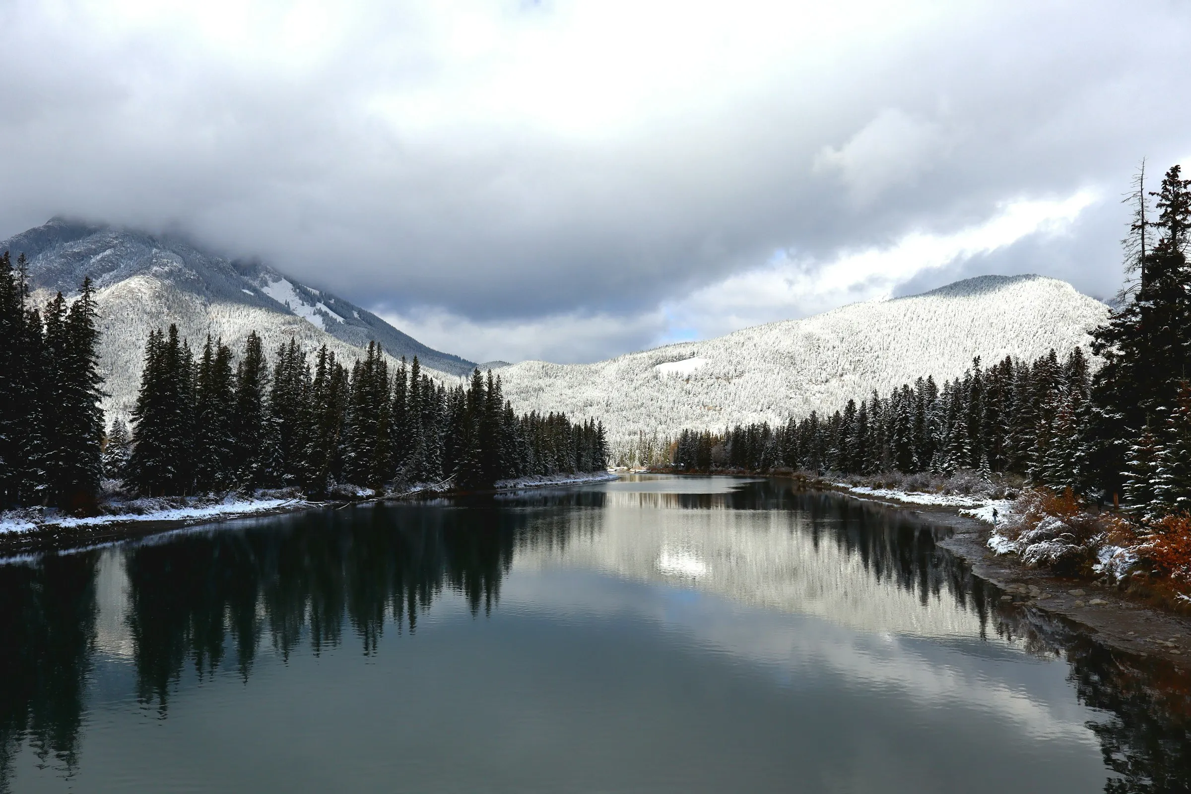 Snow-covered forest and mountains reflected in a still northern river